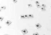 Scattered Scrabble tiles emphasize the word 'WEB' on a minimalist white background.