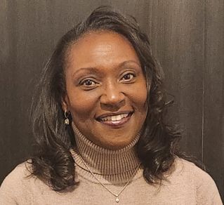 A cheerful woman with an afro hairstyle sitting indoors, showcasing happiness and style.